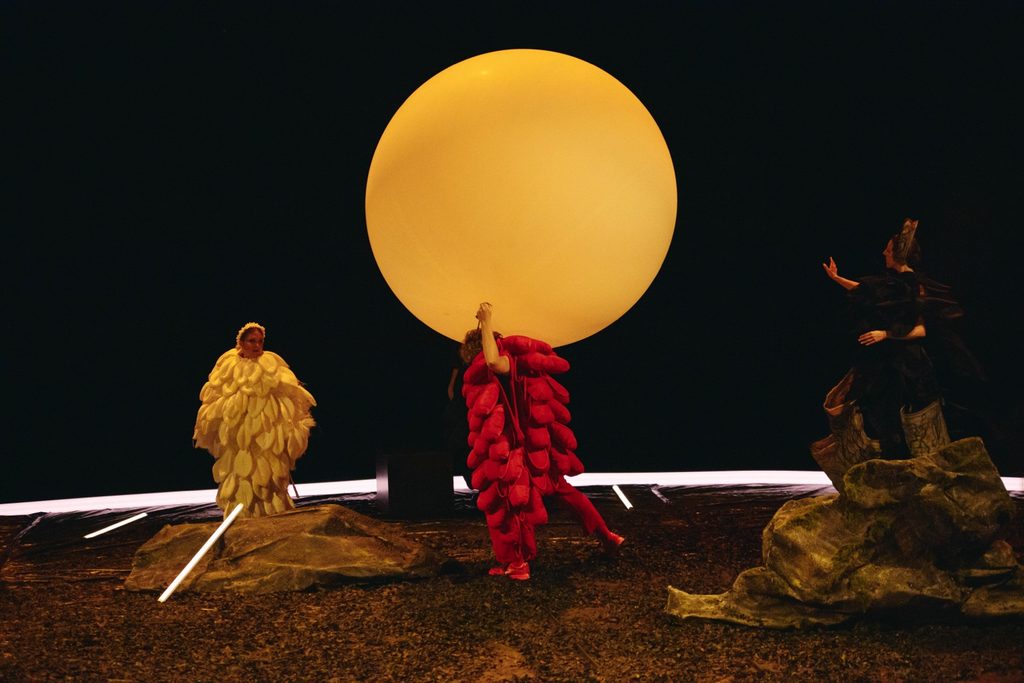 Performers in white, red and black beneath the amber sun.